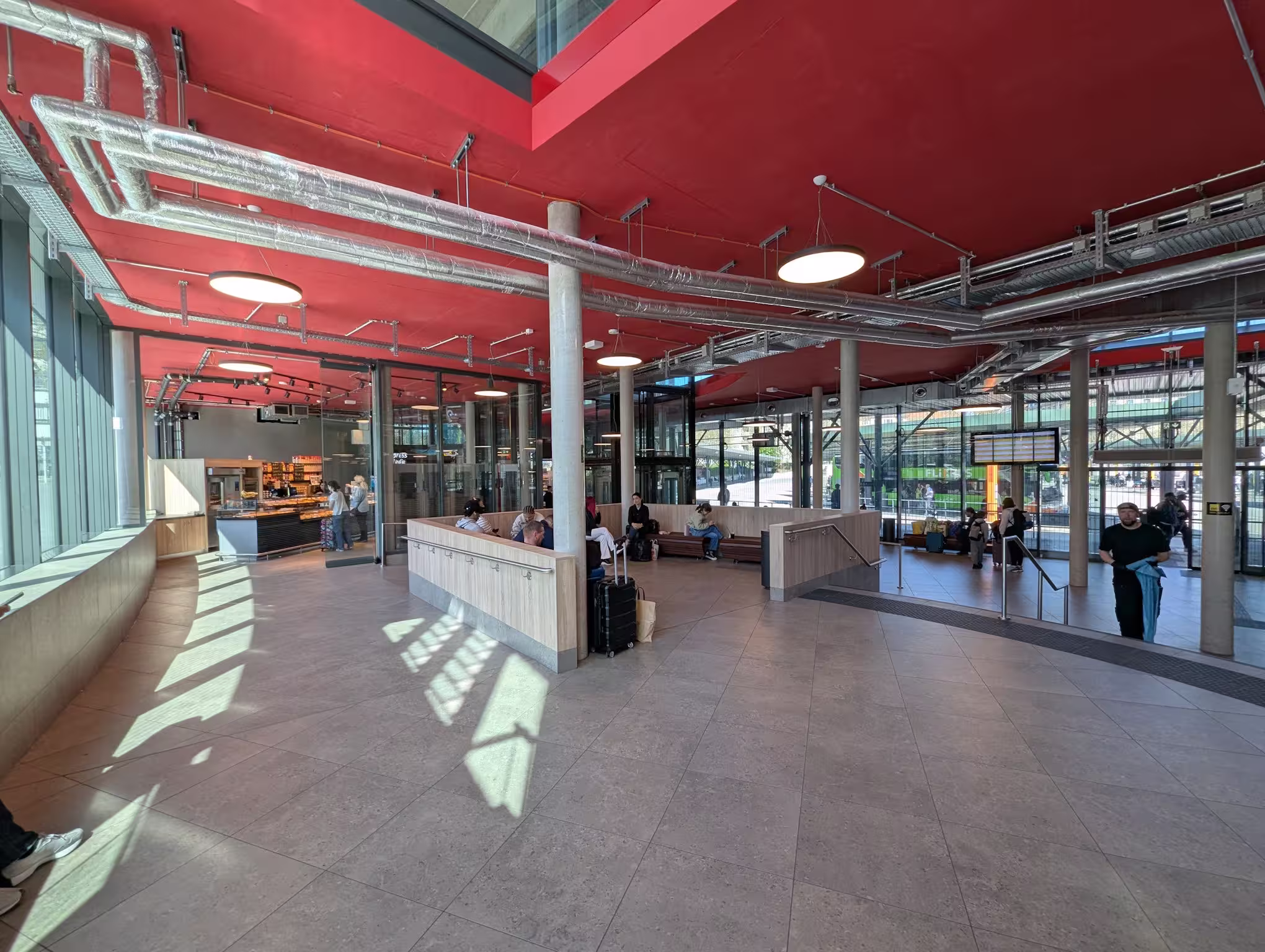 The ZOB waiting hall from the inside with a seating area, arrival board, and glass front
